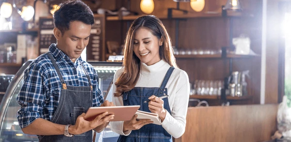 Happy young small business owner standing confidently in their store, representing growth and success.